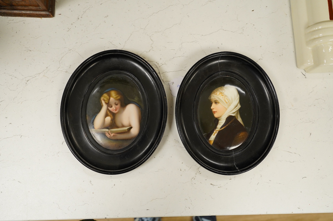 A pair of mid 19th century Paris porcelain plaques decorated with portraits of female figures, both in oval ebonised frames. Condition - fair to good